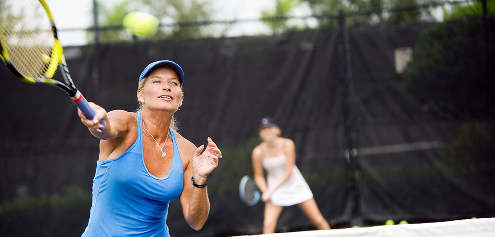 joint replacement; woman hitting a tennis ball