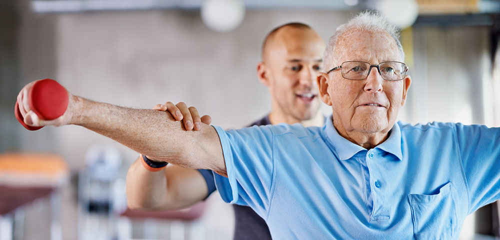 rehab / physical therapist helping a senior man stretch