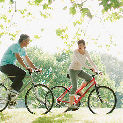 A couple riding their bikes through a park. Beaver Dam Community Hospital Blue Zones Project