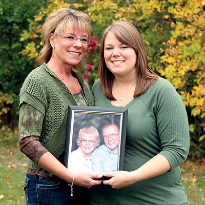Two young women hold a framed portrait of deceased loved ones. Beaver Dam Community Hospital grief support